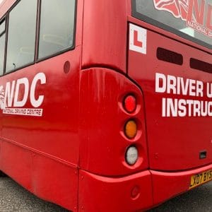 Back of red bus showing learner plate and NDC signage